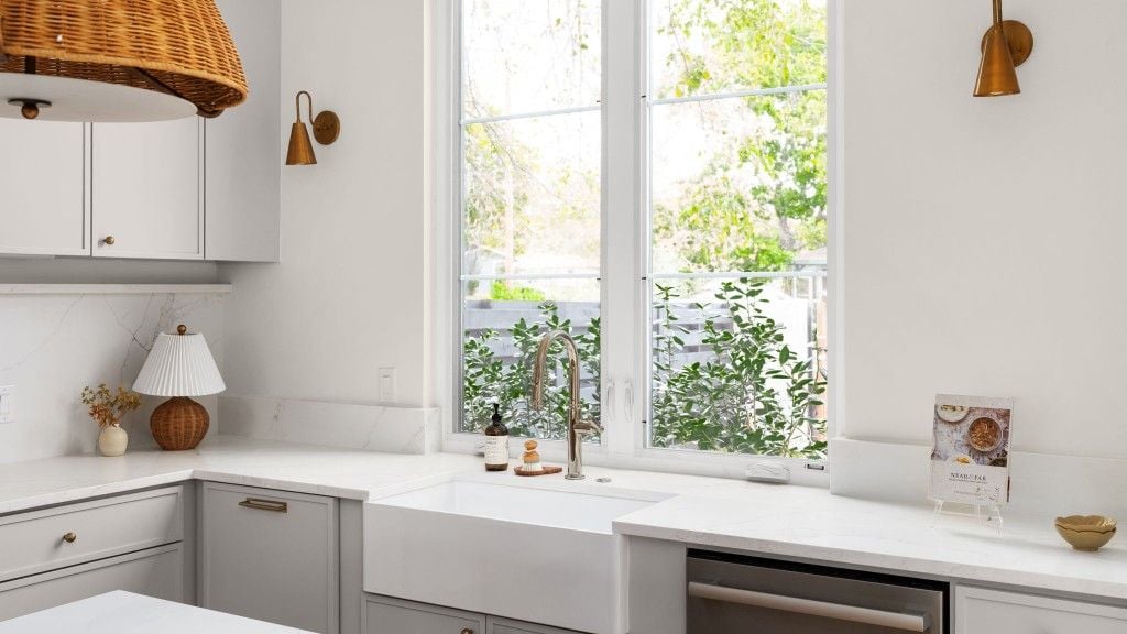 Bathroom vanity with black cabinet, arched mirror, and brass faucet