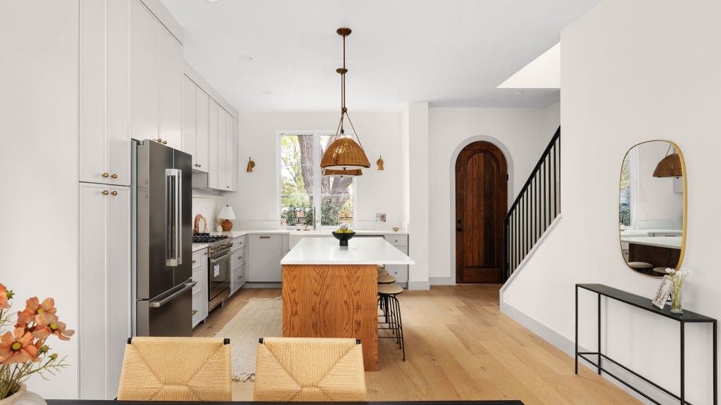 Kitchen opening to an arched wood door and stair with black railing