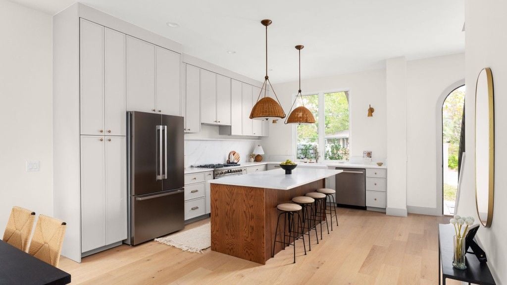 Kitchen with wood island, woven pendants, and floor-to-ceiling cabinets