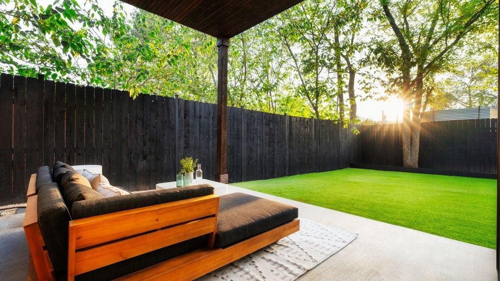 Patio seating looking toward a sunlit backyard and privacy fence